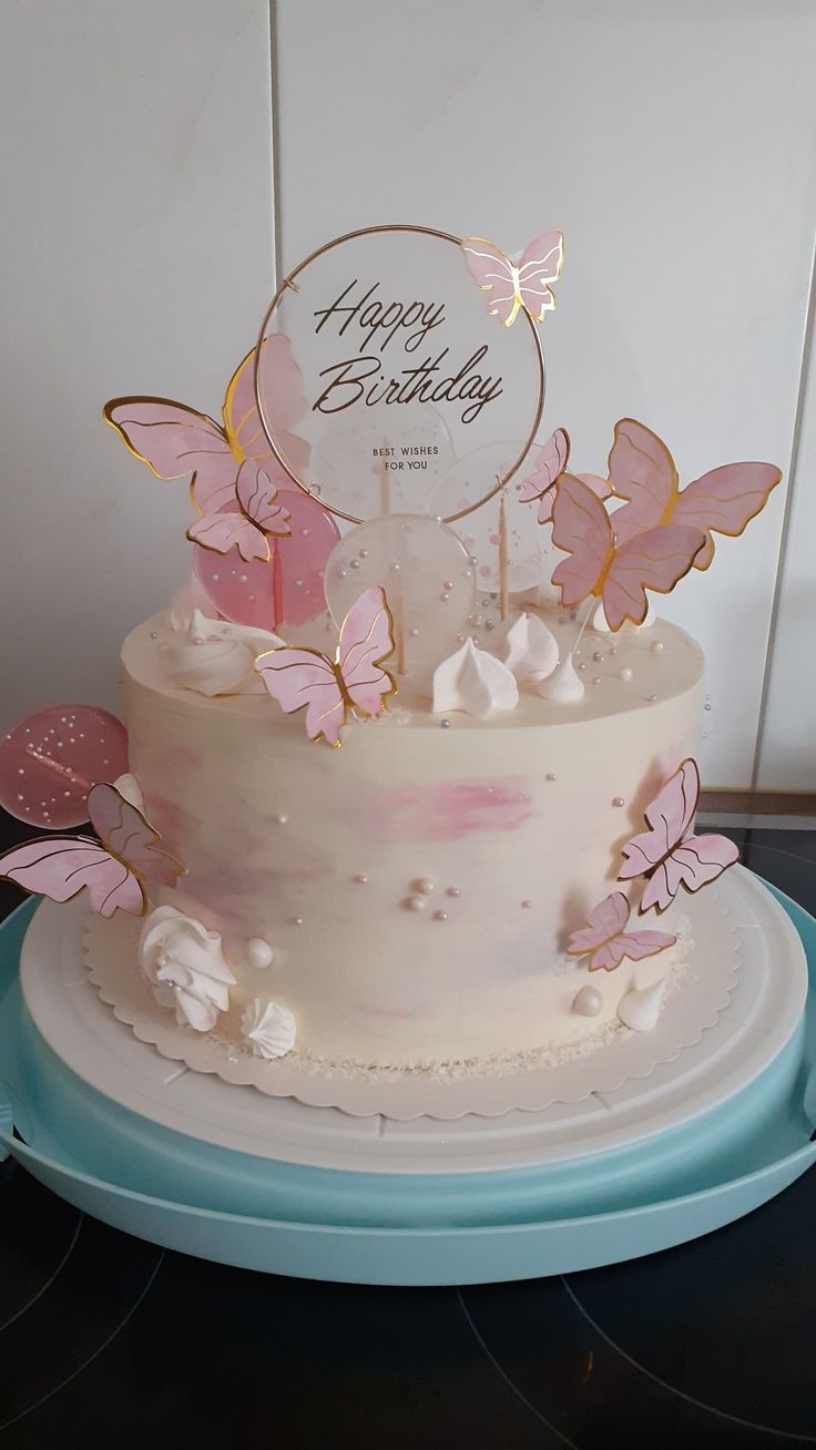 a white cake with pink butterflies on it and a happy birthday sign in the middle