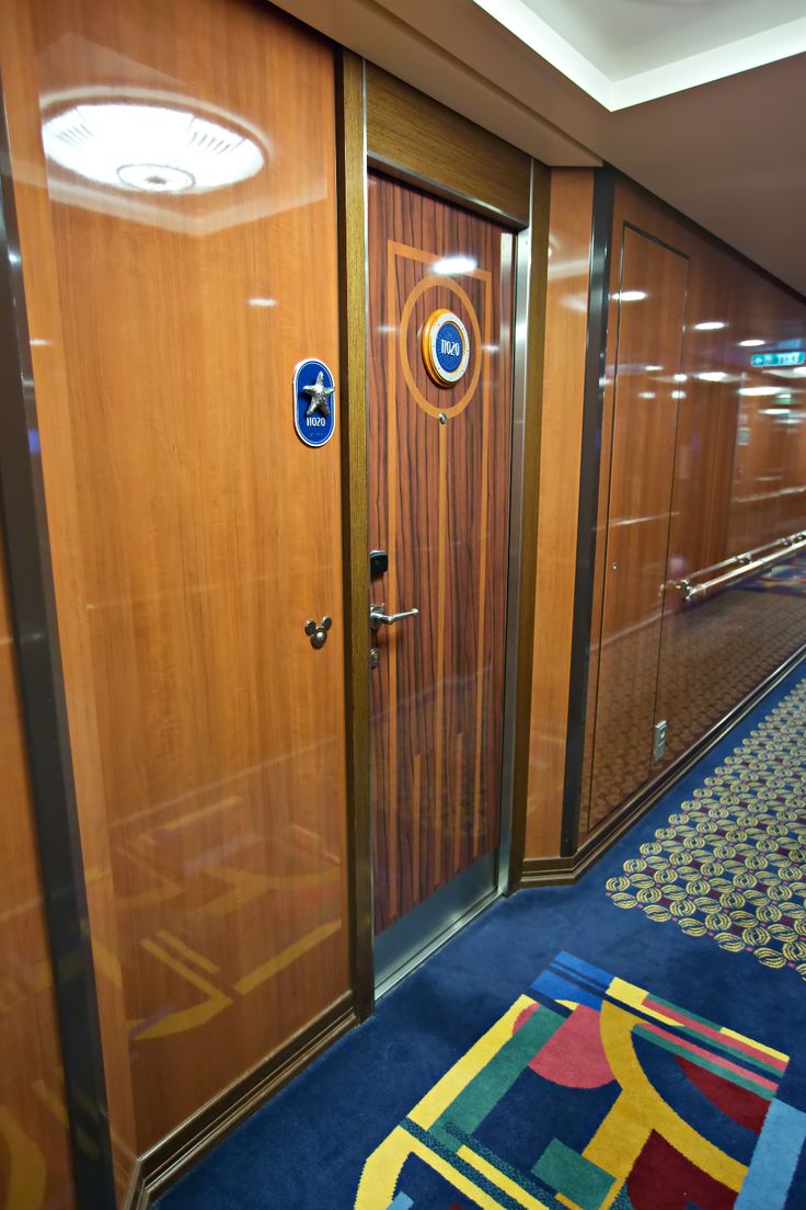 an empty hallway with wooden doors and blue carpet