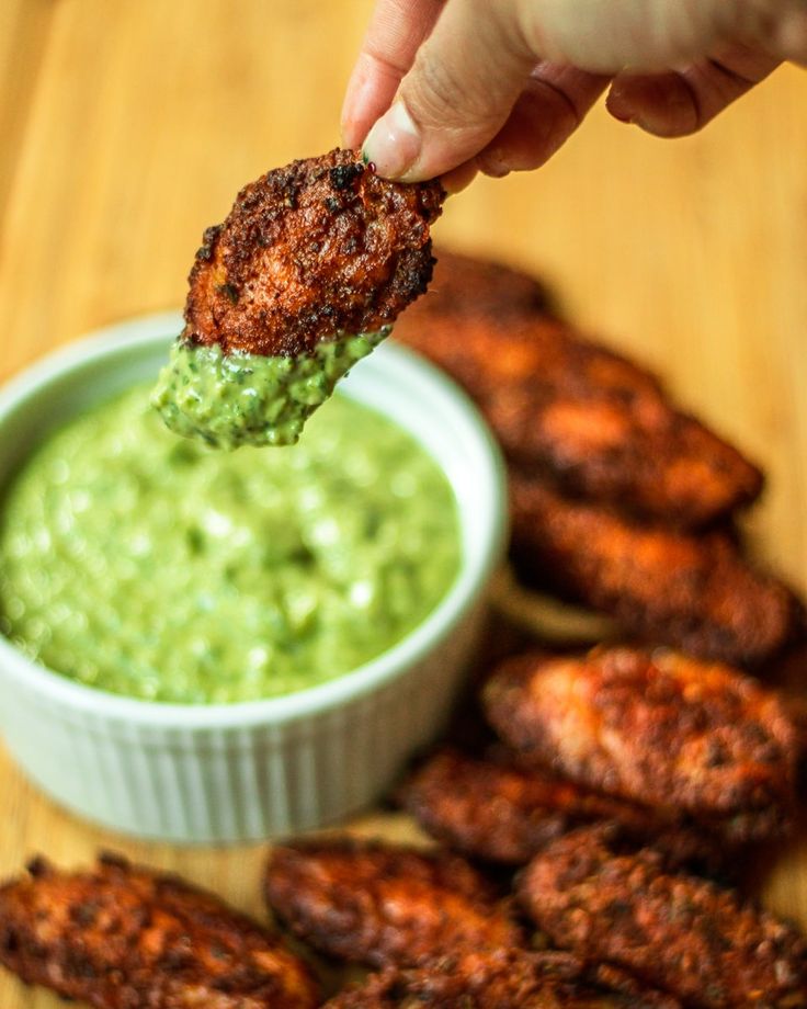 a person dipping some kind of food into a small bowl with guacamole