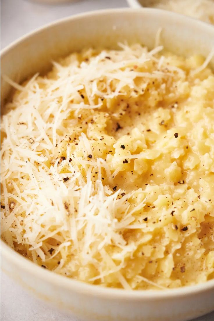 a white bowl filled with pasta and parmesan cheese