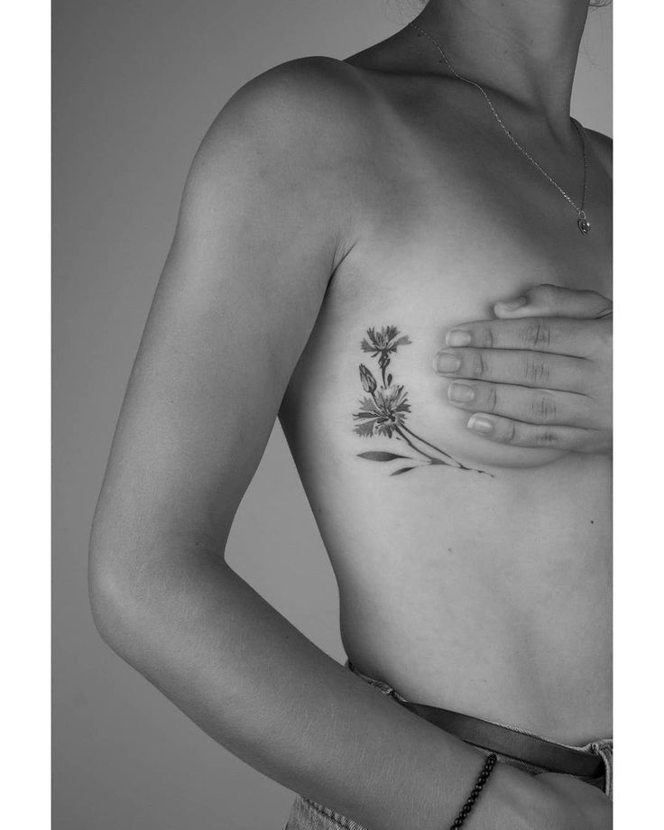 a black and white photo of a woman's chest with flowers tattooed on it