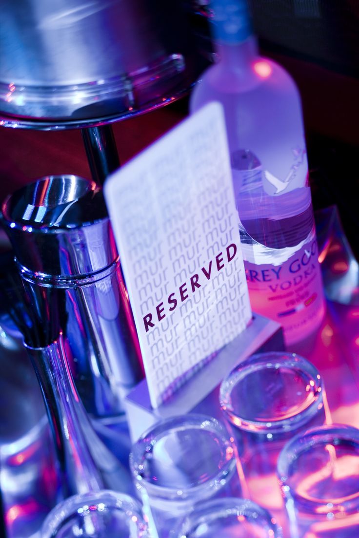 a table topped with glasses and bottles filled with liquid next to a sign that reads reserved