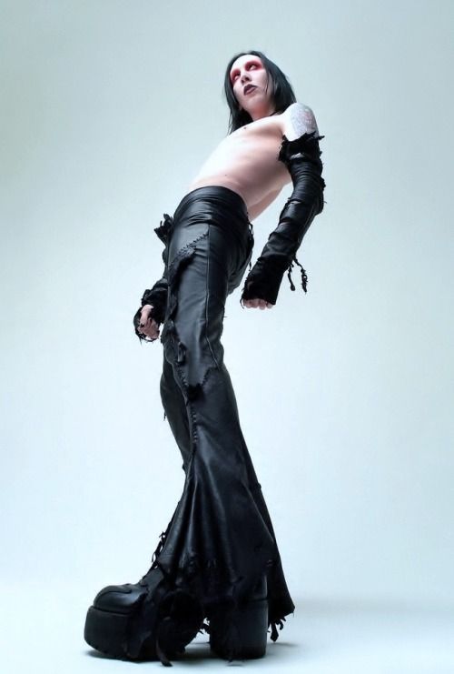 a woman in black leather pants and boots posing for a magazine cover shoot with her hands on her hips