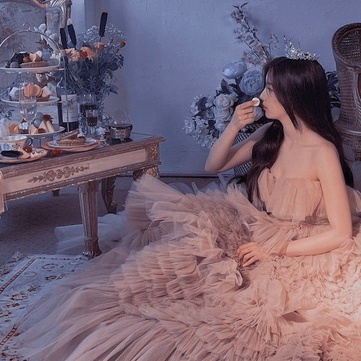 a woman in a dress sitting on the floor next to a table full of items