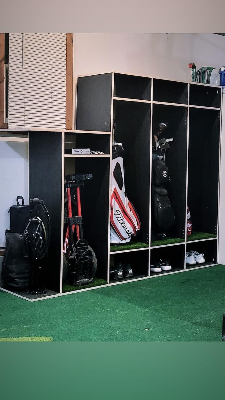 a room filled with lots of lockers and golf bags on top of green carpet