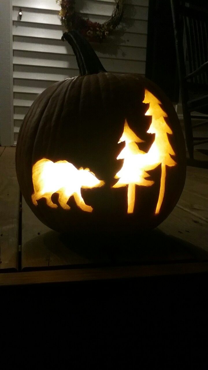 a carved pumpkin with bears and trees in the carving on it's front porch