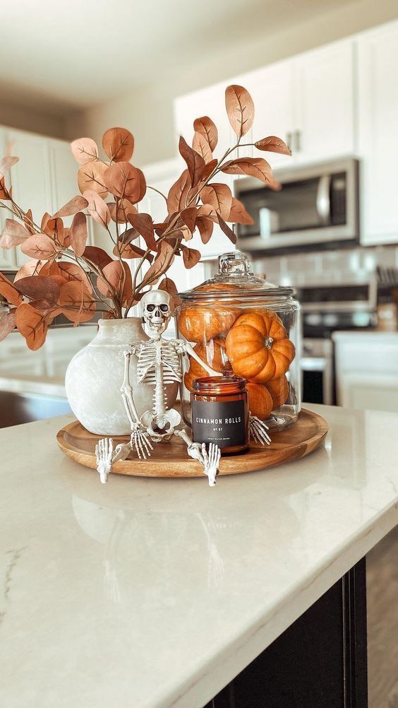 an arrangement of pumpkins and skeleton decorations on a kitchen counter