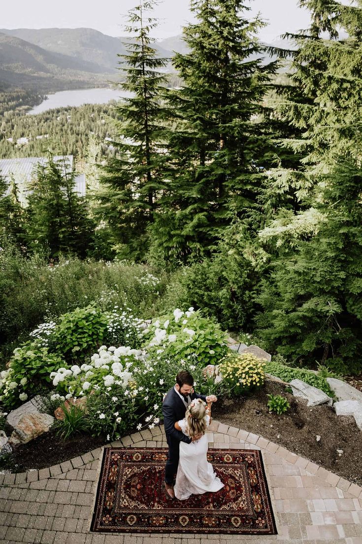 a bride and groom standing on top of a rug in the middle of a garden