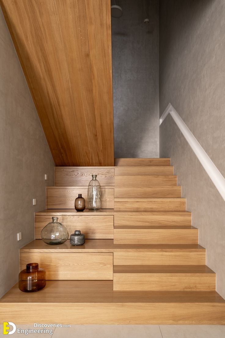 a wooden staircase leading up to the top floor with vases and jars on it