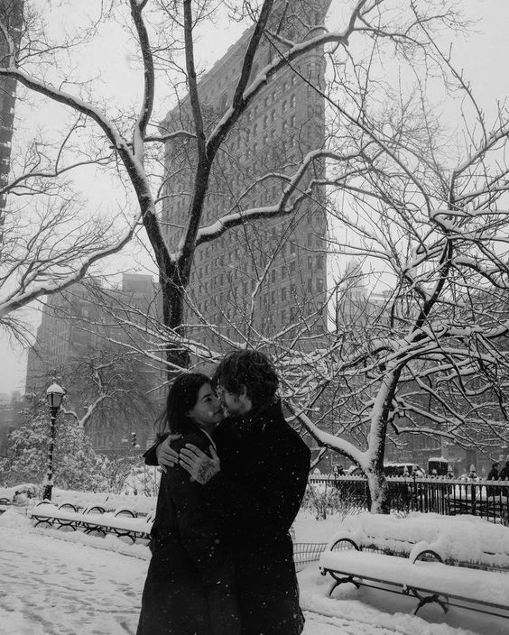 a man and woman are kissing in the snow