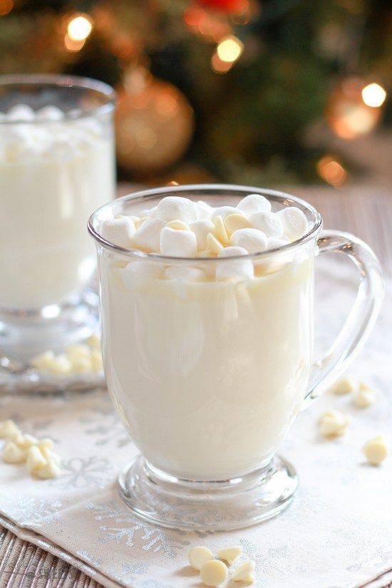 two mugs filled with hot chocolate and marshmallows sitting on a table