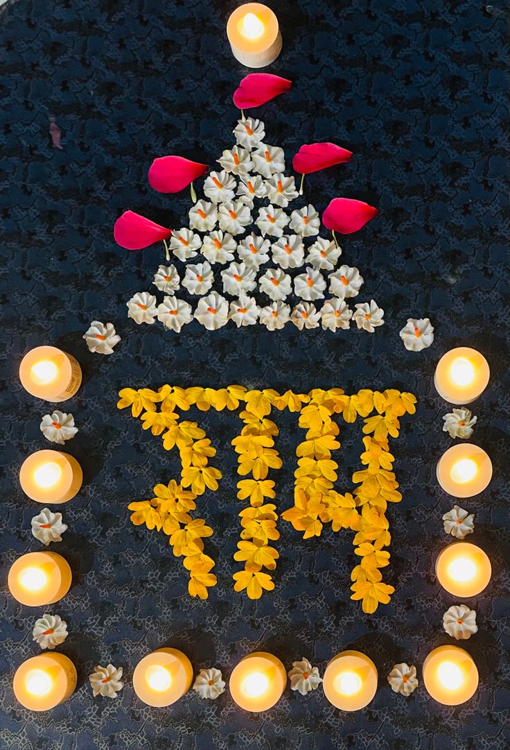 there is a lit sign that says ti in front of some flowers and candles on the ground