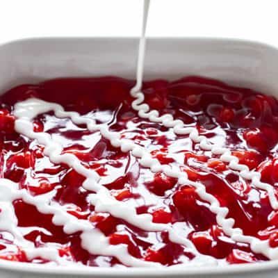 a white dish filled with cranberry sauce being drizzled with milk