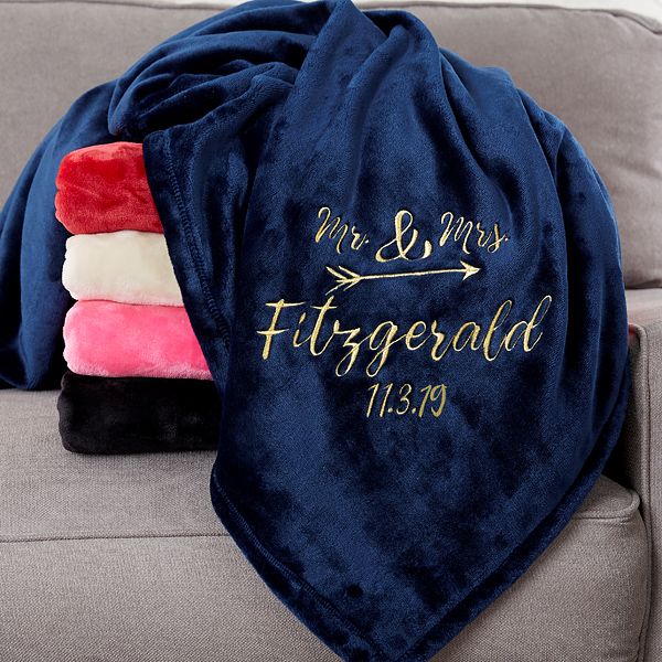 a blanket that is on top of a couch next to a pillow with the name mr and mrs fitzgerald written on it