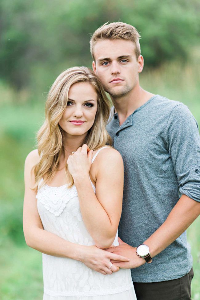 a young man and woman standing next to each other in the middle of a field