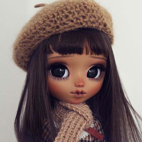 a close up of a doll wearing a hat and scarf