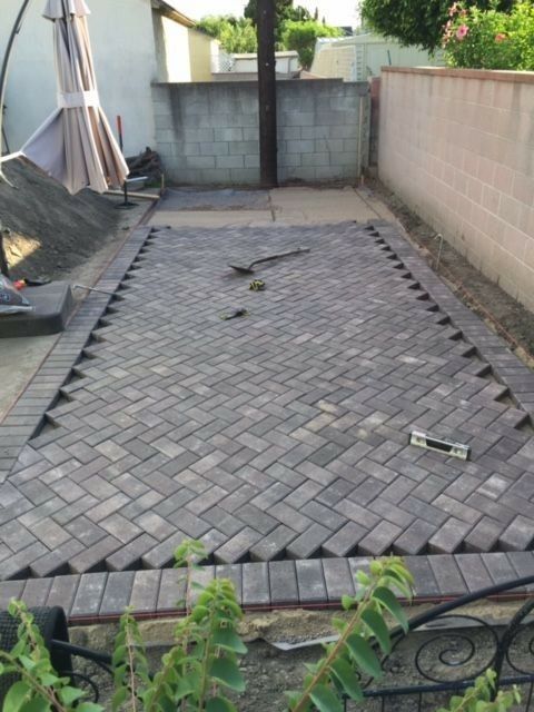 an outdoor area with brick pavers and metal fence