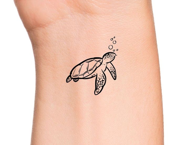 a small turtle tattoo on the wrist with bubbles coming out of its mouth and head