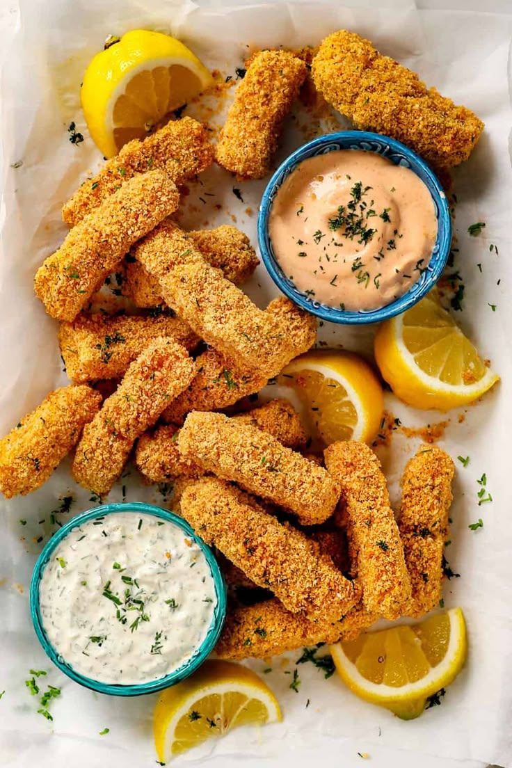 fried fish sticks with dipping sauce and lemon wedges