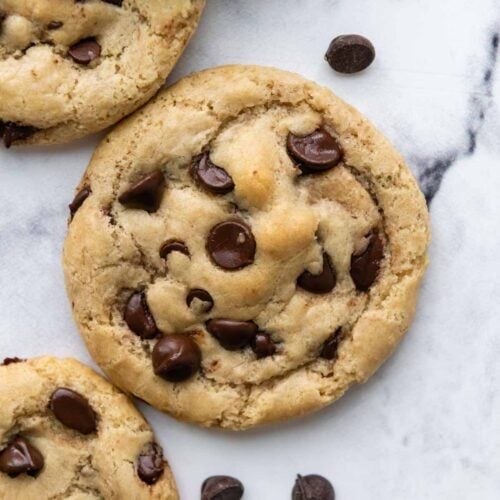 three chocolate chip cookies on a marble surface