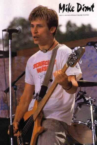 a man holding a bass guitar while standing in front of a microphone