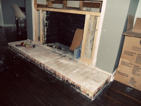 an empty fireplace in the middle of a room with boxes on the floor next to it