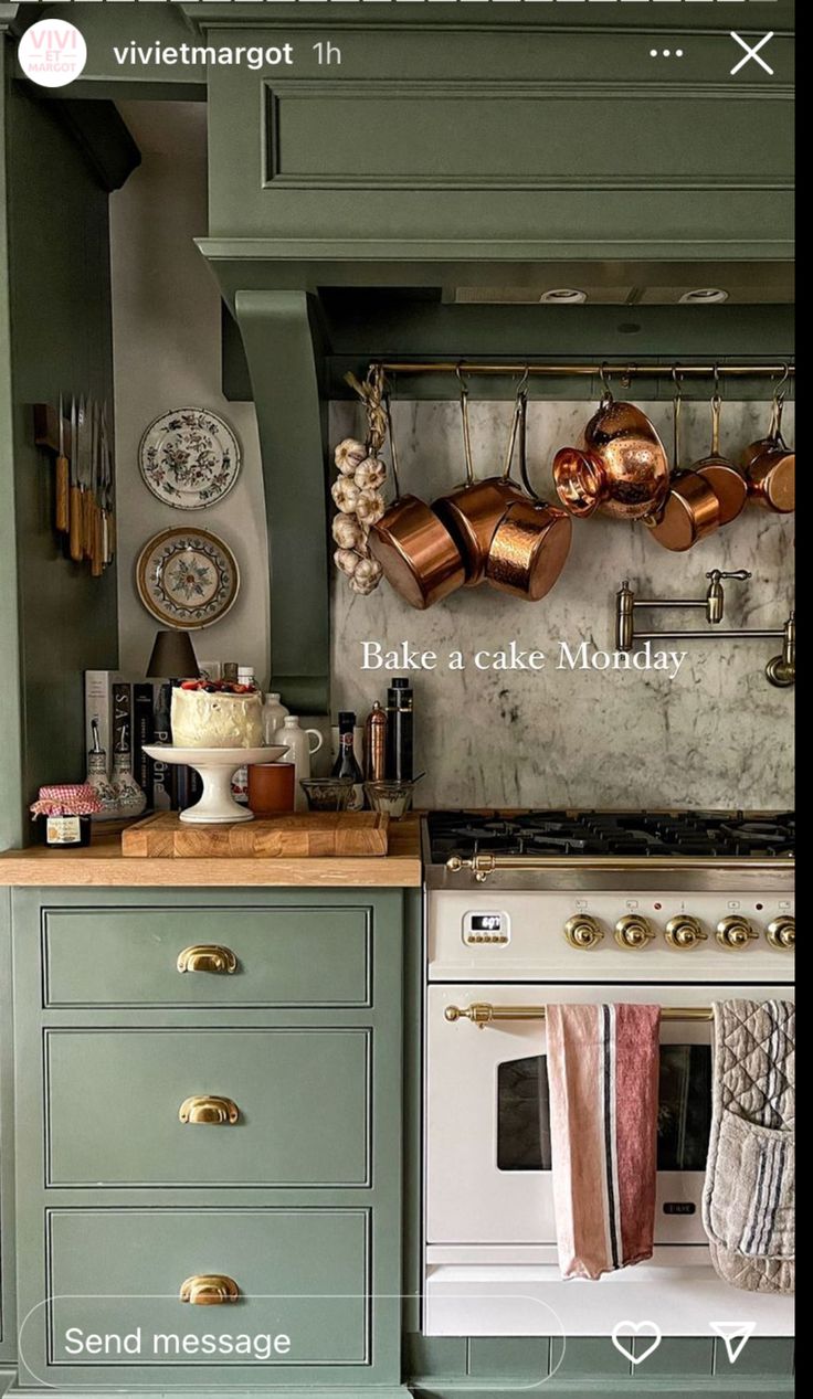 a kitchen with green cabinets and copper pots on the wall above an oven, next to a white stove