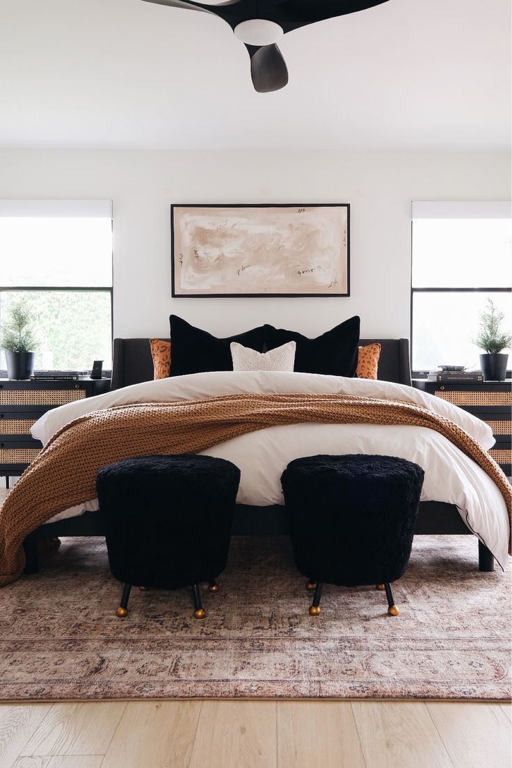 a large bed with two black chairs in front of it