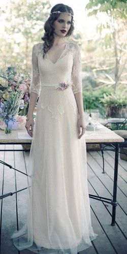 a woman in a white dress standing on a wooden floor next to a table with flowers