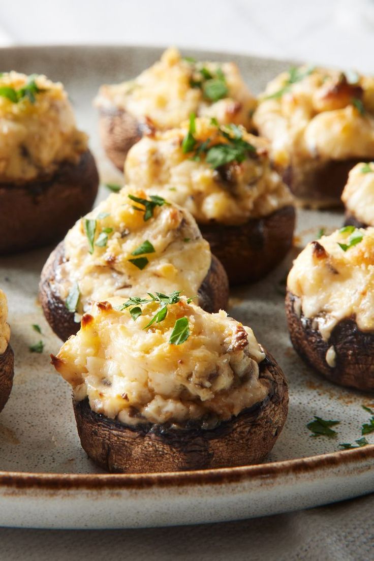 stuffed mushrooms topped with cheese and herbs on a plate