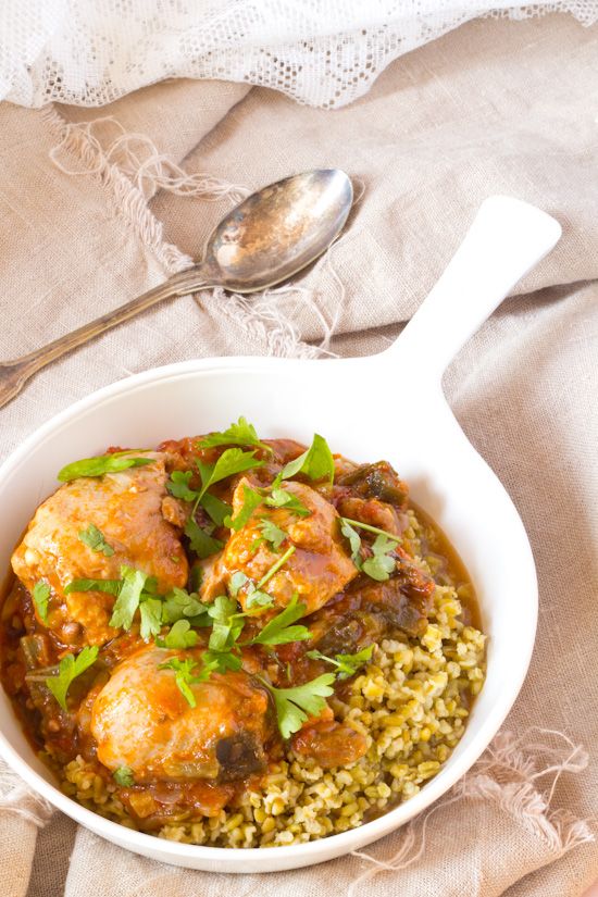 a white bowl filled with rice and meat on top of a table next to a spoon