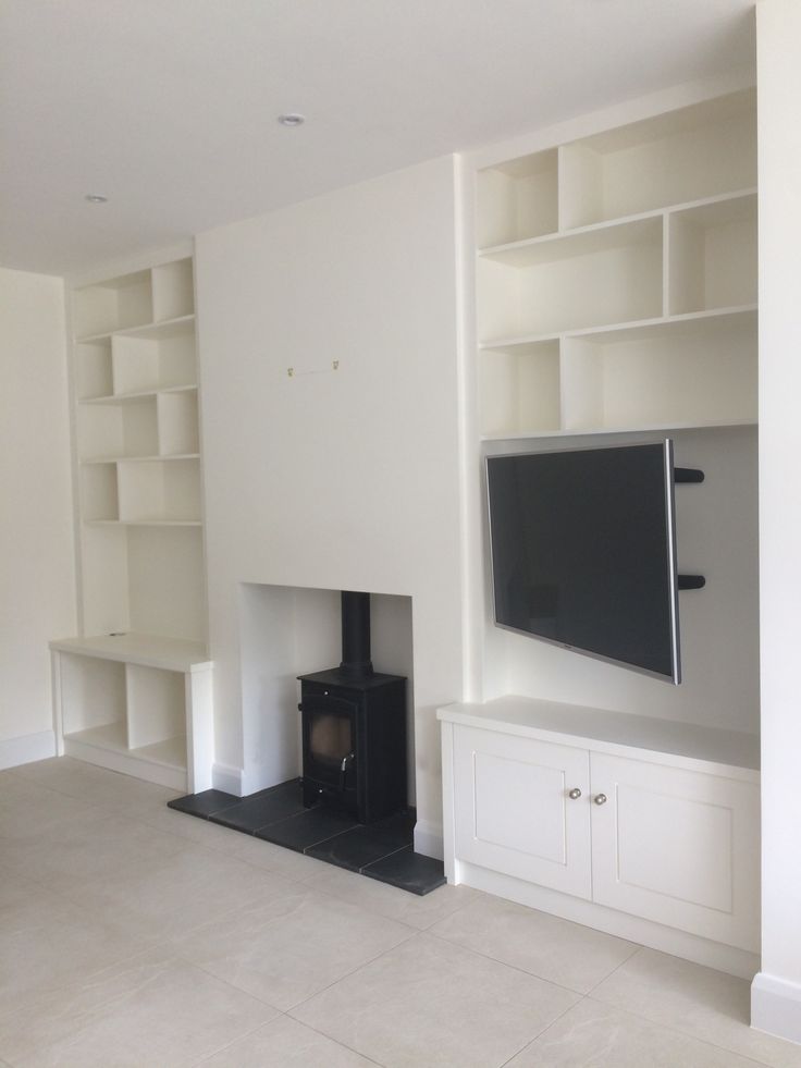 an empty living room with a fireplace and bookshelves