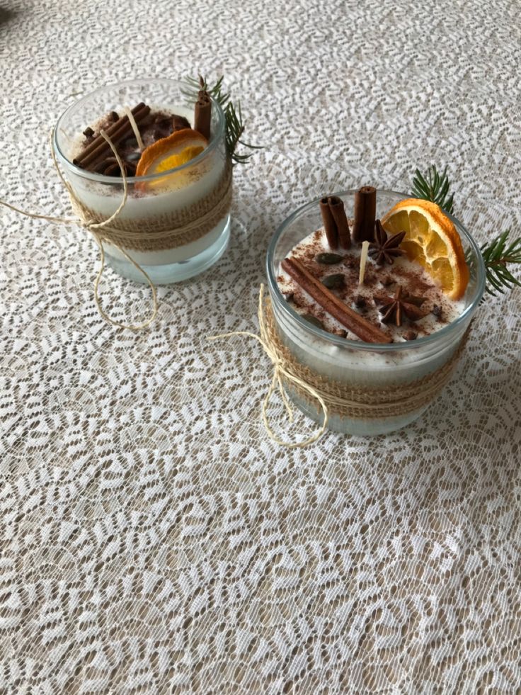 two desserts with orange slices and cinnamon sticks in glass bowls on a tablecloth