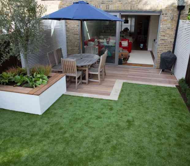 a small backyard with grass and an umbrella over the table in it's center