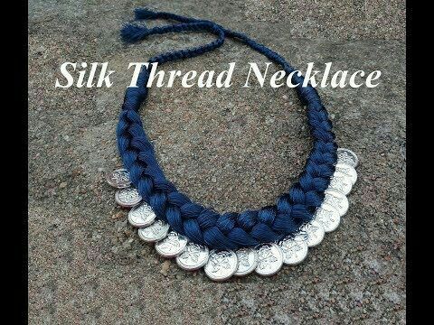 a blue necklace with silver coins on it and the words silk thread necklace written in white