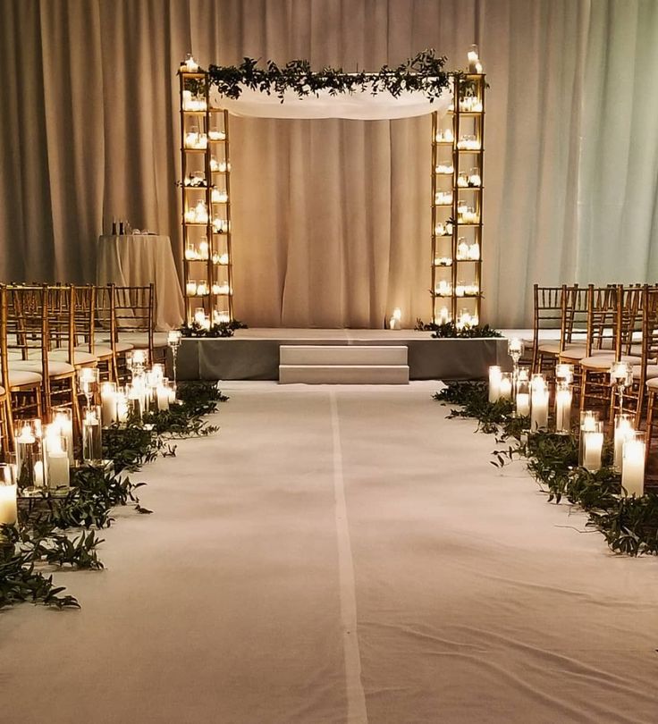 the aisle is lined with candles and greenery for an elegant wedding ceremony at night