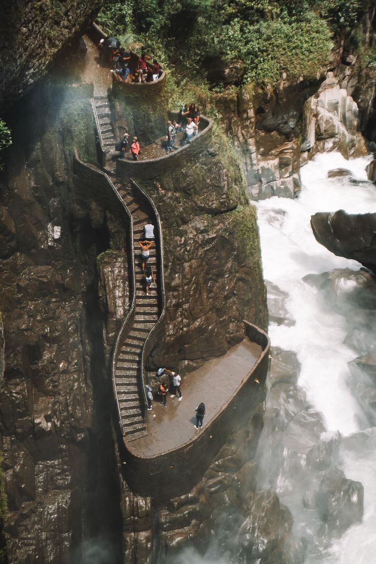 people are standing on the side of a waterfall while others look at them from above