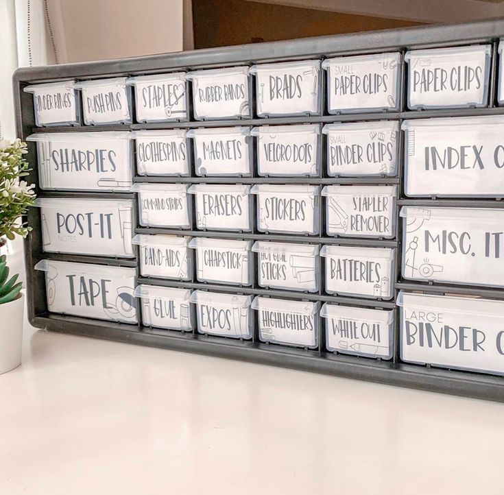 a large stack of white and black labels on a shelf next to a potted plant