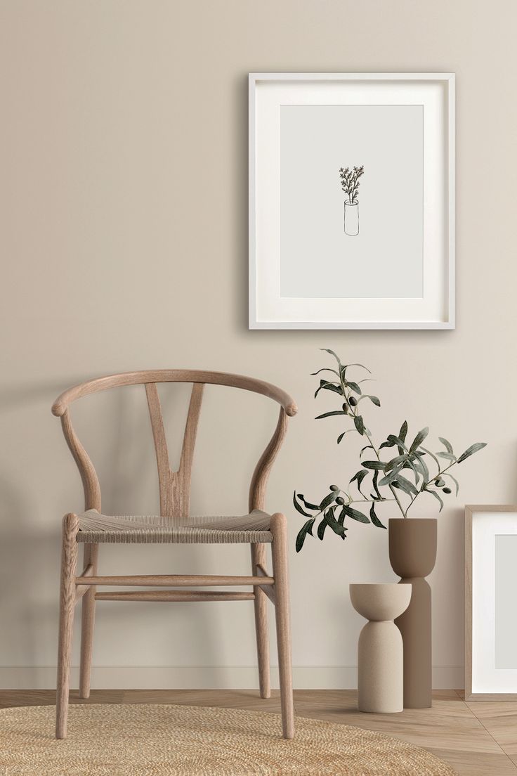 an empty chair next to a potted plant in front of a white framed photograph