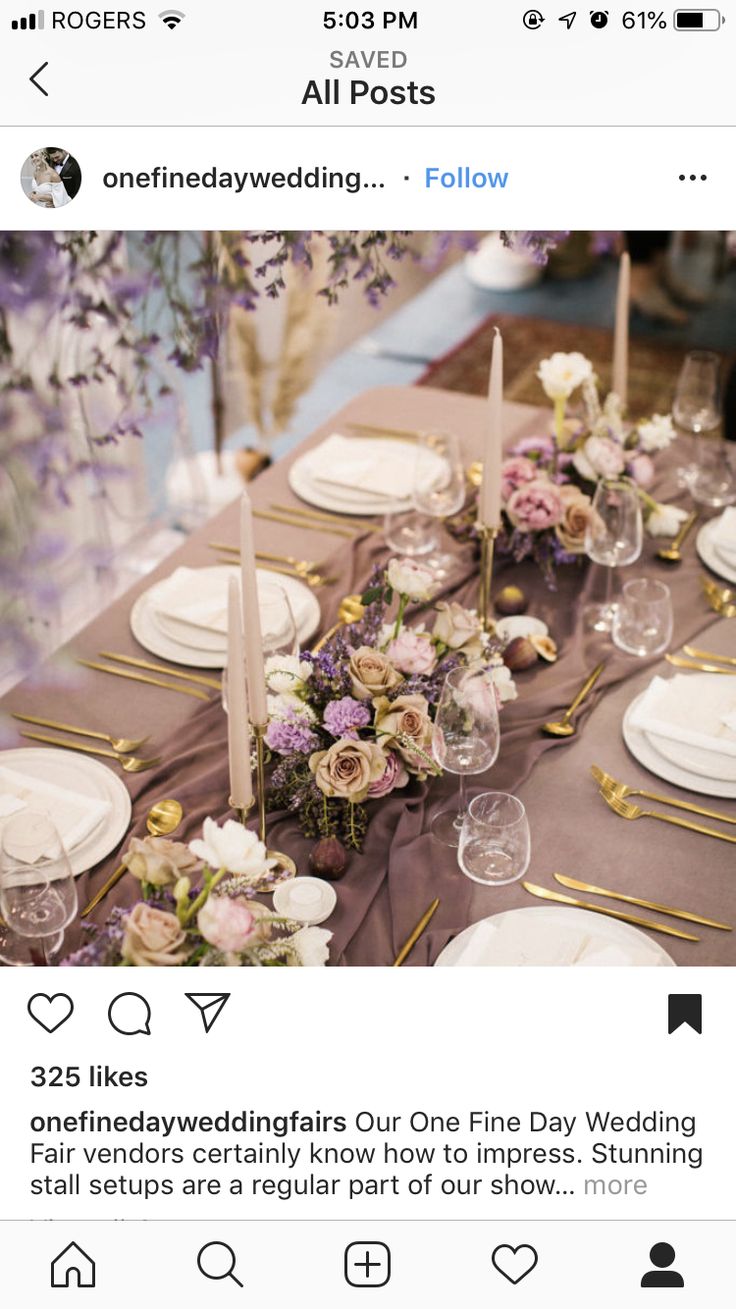 the table is set with white plates and purple napkins, silverware and flowers