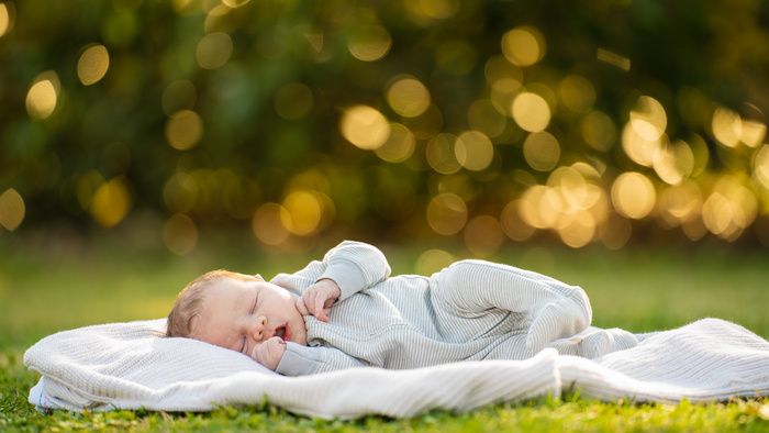 a baby laying on top of a blanket in the grass