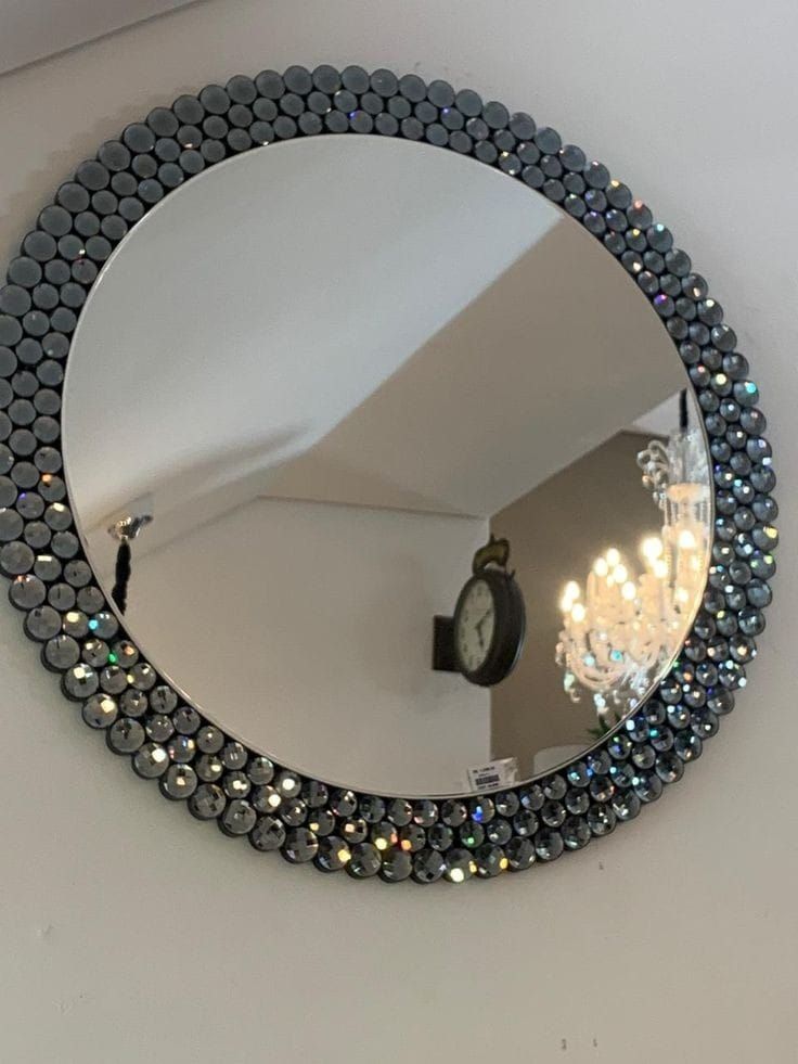 a round mirror hanging on the wall with a chandelier in front of it