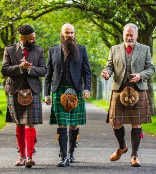 three men in kilts are walking down the street with one man wearing a long beard