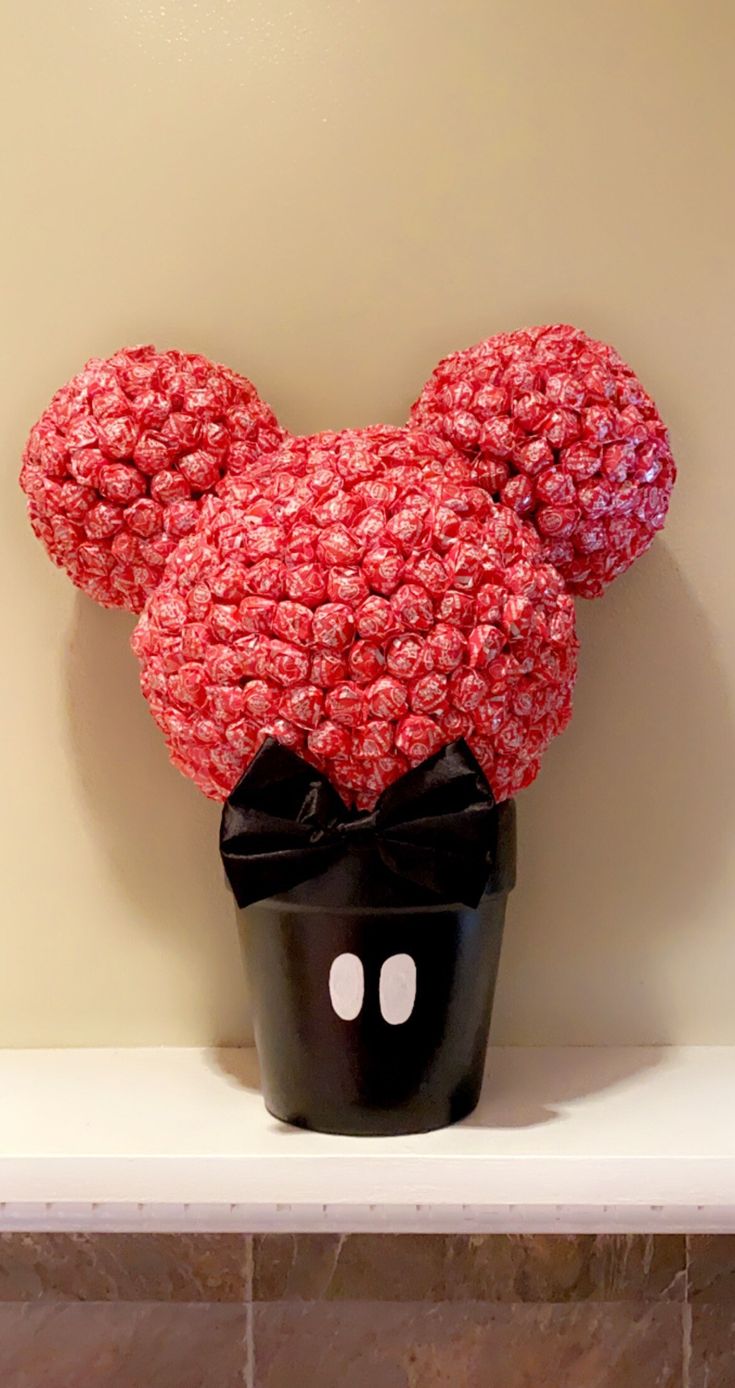 a mickey mouse head made out of flowers on top of a shelf in a bathroom