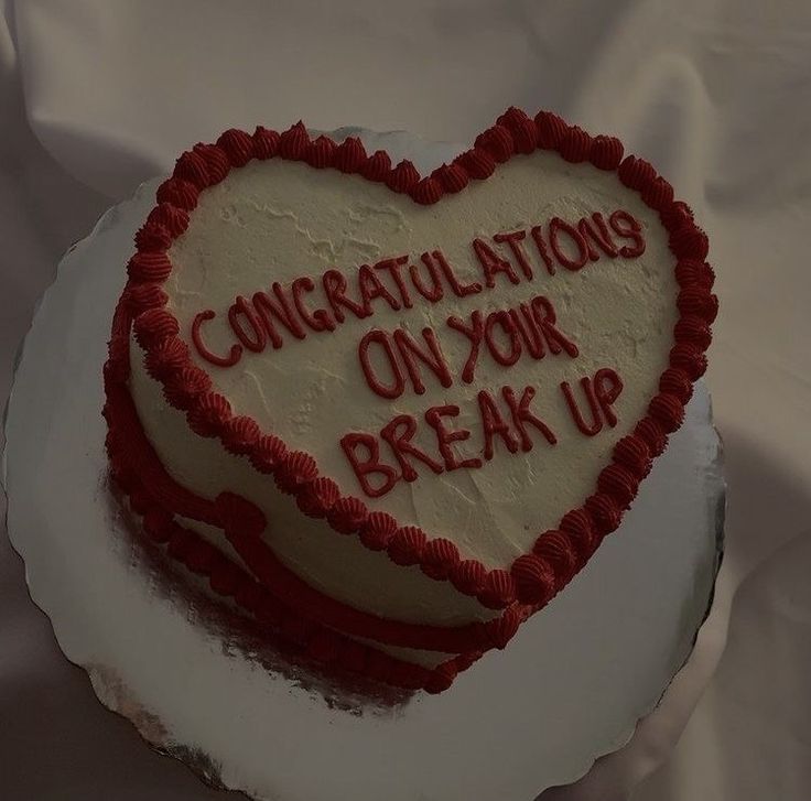 a heart shaped cake with congratulationss on your break up written in red and white frosting