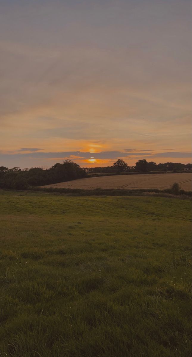 the sun is setting over an open field