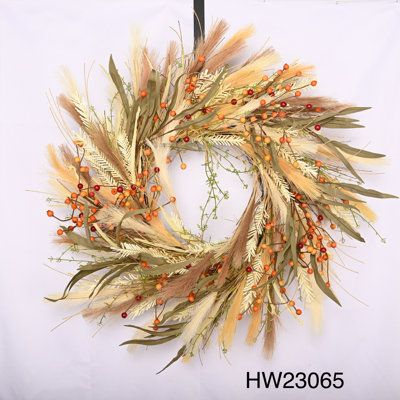 a dried wreath with orange berries and green leaves