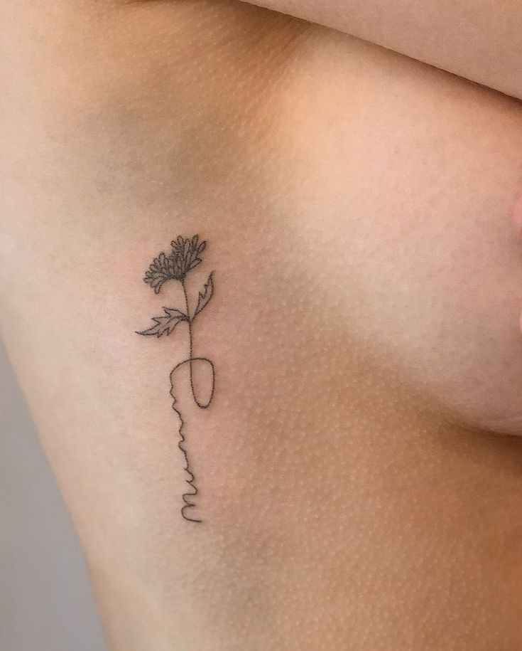 a woman's breast with a flower tattoo on her left side ribcage