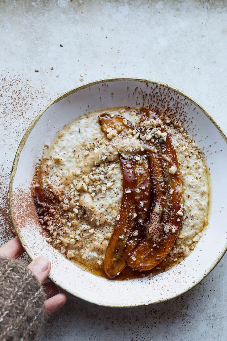 a bowl filled with oatmeal topped with sliced banana's and powdered sugar