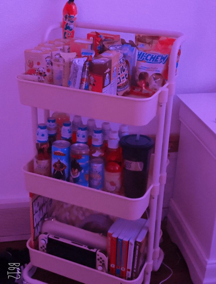 a pink cart filled with lots of food and drinks next to a white refrigerator freezer